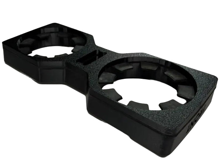 A black molded plastic dual cup holder frame with textured foam inserts, shown on a neutral light gray background.